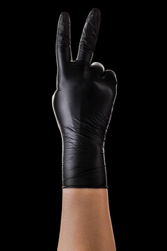 Hand in black gloves showing two fingers up in peace or victory symbol on black