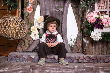little boy wearing retro costume on the doorstep of a toy house