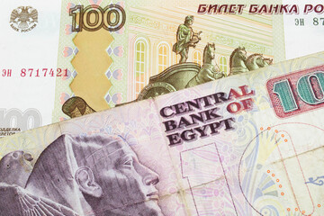 A macro image of a Russian one hundred ruble note paired up with a pink and purple ten pound bank note from Egypt.  Shot close up in macro.
