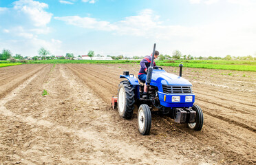 Obraz premium A farmer riding a tractor on a farm field. Farming and work in the agricultural industry. Cultivating land soil for further planting. Using technology to facilitate work and increase efficiency