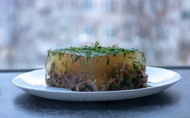 Russian aspic jelly with greens on a white plate.food