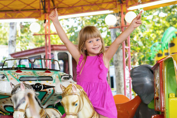 Beautiful little girl on a retro carousel ride