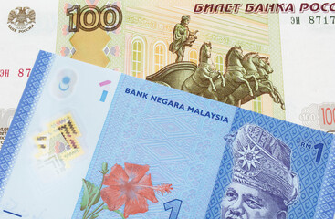 A macro image of a Russian one hundred ruble note paired up with a blue, plastic one ringgit bank note from Malaysia.  Shot close up in macro.