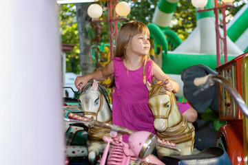 Fototapeta na wymiar Beautiful little girl on a retro carousel ride