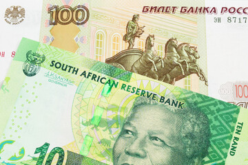 A macro image of a Russian one hundred ruble note paired up with a shiny, green 10 rand bill from South Africa.  Shot close up in macro.