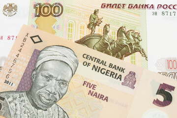 A macro image of a Russian one hundred ruble note paired up with a orange, plastic five naira note from Nigeria.  Shot close up in macro.