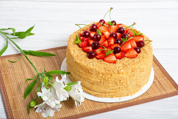 Beautiful napoleon cake with strawberries and cherries mixed with i mint on a light background