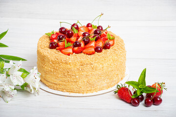 Beautiful napoleon cake with strawberries and cherries mixed with i mint on a light background