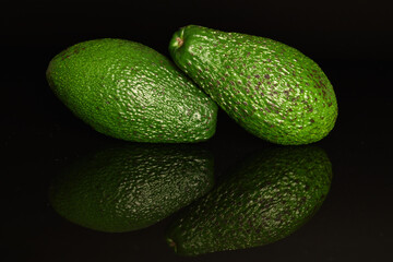 Green fresh ripe tasty avocado, close-up, on a black background.