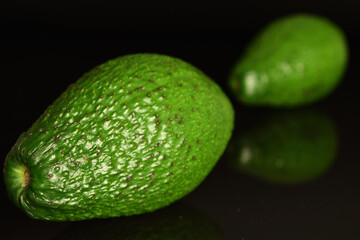 Green fresh ripe tasty avocado, close-up, on a black background.