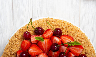 Beautiful napoleon cake with strawberries and cherries mixed with i mint on a light background