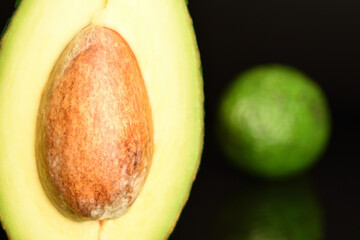 Green fresh ripe tasty avocado, close-up, on a black background.