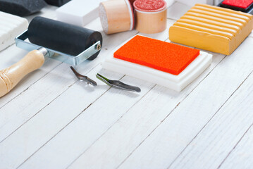 handicraft equipments, ink pads, lino cutter, paint roller and plasticine blocks on white wood table
