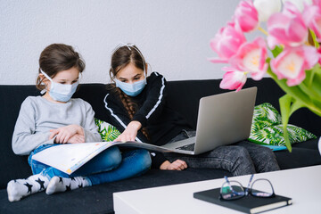 Online education, distance learning, homeschooling. Children in protective mask studying homework online lesson at home in tablet of laptop and holding videocall. Social distance on quarantine. 