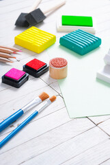 pencils, painting brushes, plasticine blocks and ink pads on white wood