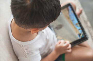 Penang, Malaysia - January 14, 2020 : Little kid's using digital touchscreen phone tablet computer playing games.