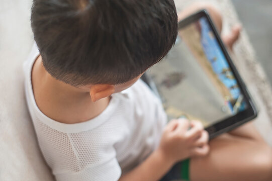 Penang, Malaysia - January 14, 2020 : Little kid's using digital touchscreen phone tablet computer playing games.