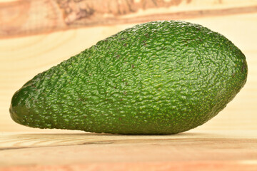 Green fresh ripe tasty avocado, close-up, on a background of natural wood.