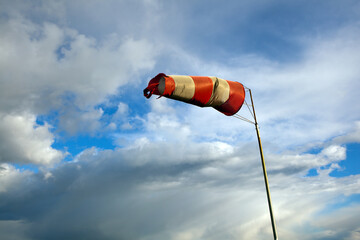 Meteorology wind bag for marine navigation. Red and white windsock blows against a blue sky
