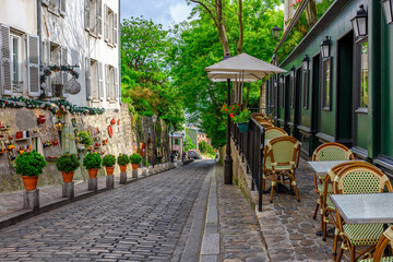 Fototapeta premium Przytulna ulica ze stolikami kawiarni w dzielnicy Montmartre w Paryżu, Francja