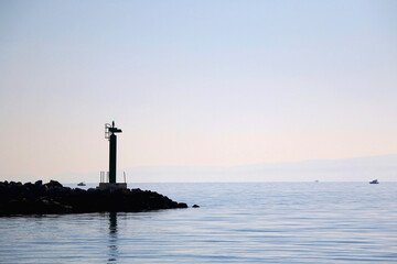 Silhouette of a small lighthouse on a pier in Split, Croatia.