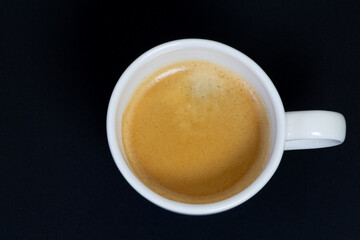 White cup of coffee from the zenith on black background