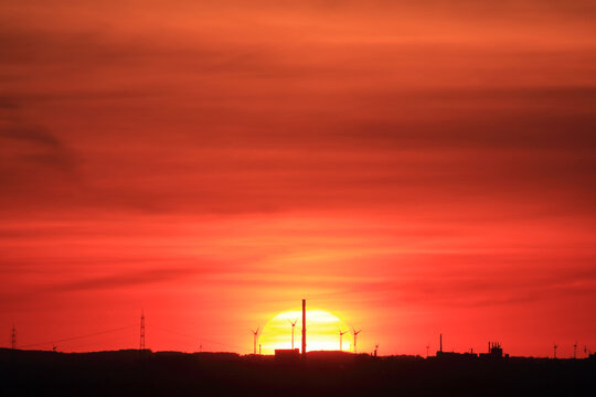 Silhouette einer Industrielandschaft vor roter Sonne