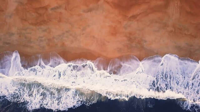 Flying over a sandy beach. Waves break on a sandy beach on the Atlantic coast, aerial View. Nazare, Portugal.