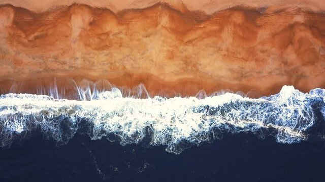 Flying over a sandy beach. Waves break on a sandy beach on the Atlantic coast, aerial View. Nazare, Portugal.