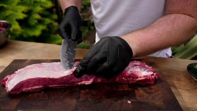 A man cuts meat with a knife and separates fat. 4K shooting