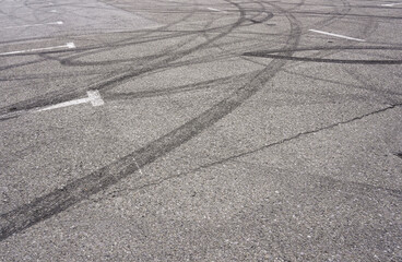 Asphalt texture with white line and tire marks.  Smooth asphalt road. Tarmac dark grey grainy road background.Top view