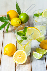 Concept of summer refreshing healthy alcohol free homemade lemonade with fresh pepper mint, limes and lemons. Low calories cold detox beverage. Wooden background, closeup