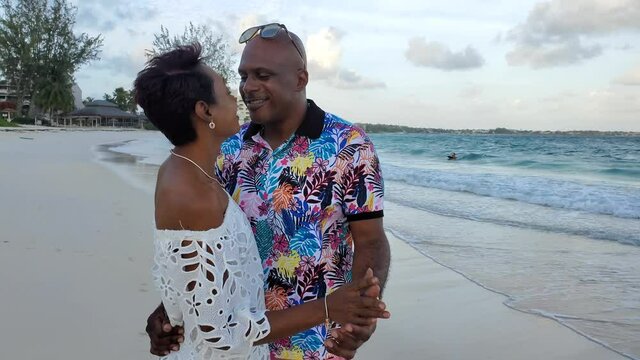Black African American Married Couple on romantic walk on tropical island honeymoon anniversary beach sunset love / kiss drama scene