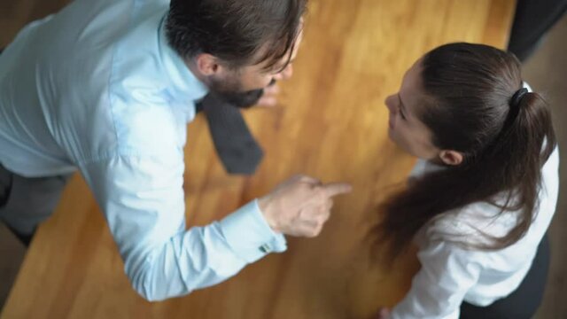 Top view. Work violence. A man yells at a subordinate leaning on the table. The girl in raised tones responds to the screams of the boss standing against him. Gender Conflict Concept. Prores 422.