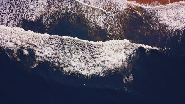 Flying over a sandy beach. Waves break on a sandy beach on the Atlantic coast, aerial View. Nazare, Portugal.