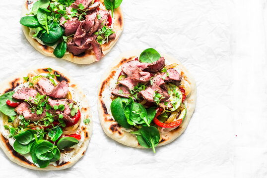 Grilled vegetables and steak flatbread tacos. Delicious appetizer, tapas, snack on a light background, top view. Copy space