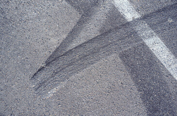Fototapeta premium Asphalt texture with white line and tire marks. Smooth asphalt road. Tarmac dark grey grainy road background.Top view