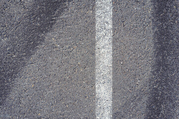 Asphalt texture with white line and tire marks. Smooth asphalt road. Tarmac dark grey grainy road background.Top view