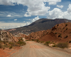 Desert dirt road in the arid landscape. Route across the dry and empty valley, into the red mountains. 