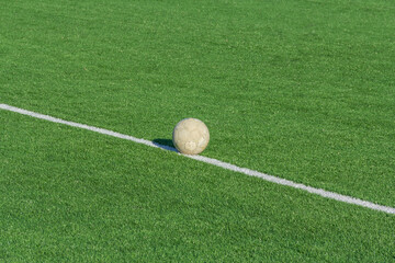 Green grass and white border lines on football ground. Soccer field on artificial turf. Artificial green grass texture. Artificial football field in an open stadium