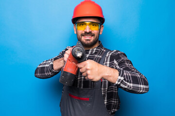 Portrait of bearded handyman with electric drill isolated on blue background