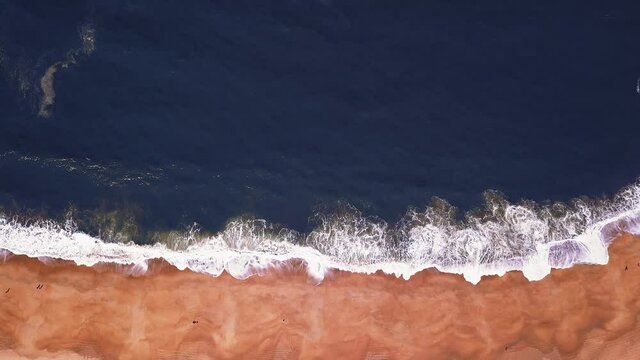 Flying over a sandy beach. Waves break on a sandy beach on the Atlantic coast, aerial View. Nazare, Portugal.