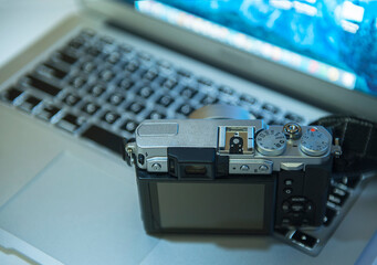 Kuala Lumpur, Malaysia - May 23, 2020 : Digital mirror less camera on top laptop. Concept of photographer work station.