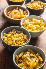 Various types of raw italian pasta in bowls.