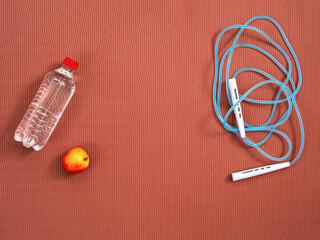 Skipping rope, bottle of water on the mat, top view with copy space. Healthy lifestyle, fitness cardio workout. Layout