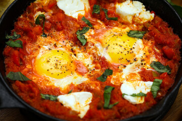 Shakshuka. Fried eggs in tomato sauce, with tomatoes and hot peppers, in a cast-iron frying pan.
