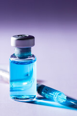 Close-up of a medical bottle with a blue liquid and a syringe