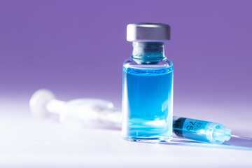 Close-up of a medical bottle with a blue liquid and a syringe