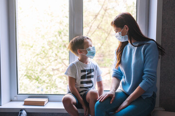 Son and mother sitting by a window during coronavirus quarantine.