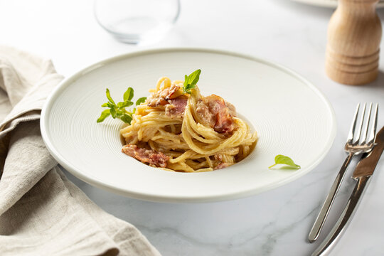 Pasta carbonara served in deep white plate with oregano